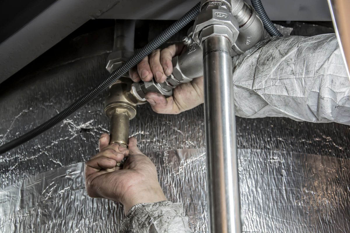 Hands tightening a brass fitting on a steel water pipe
