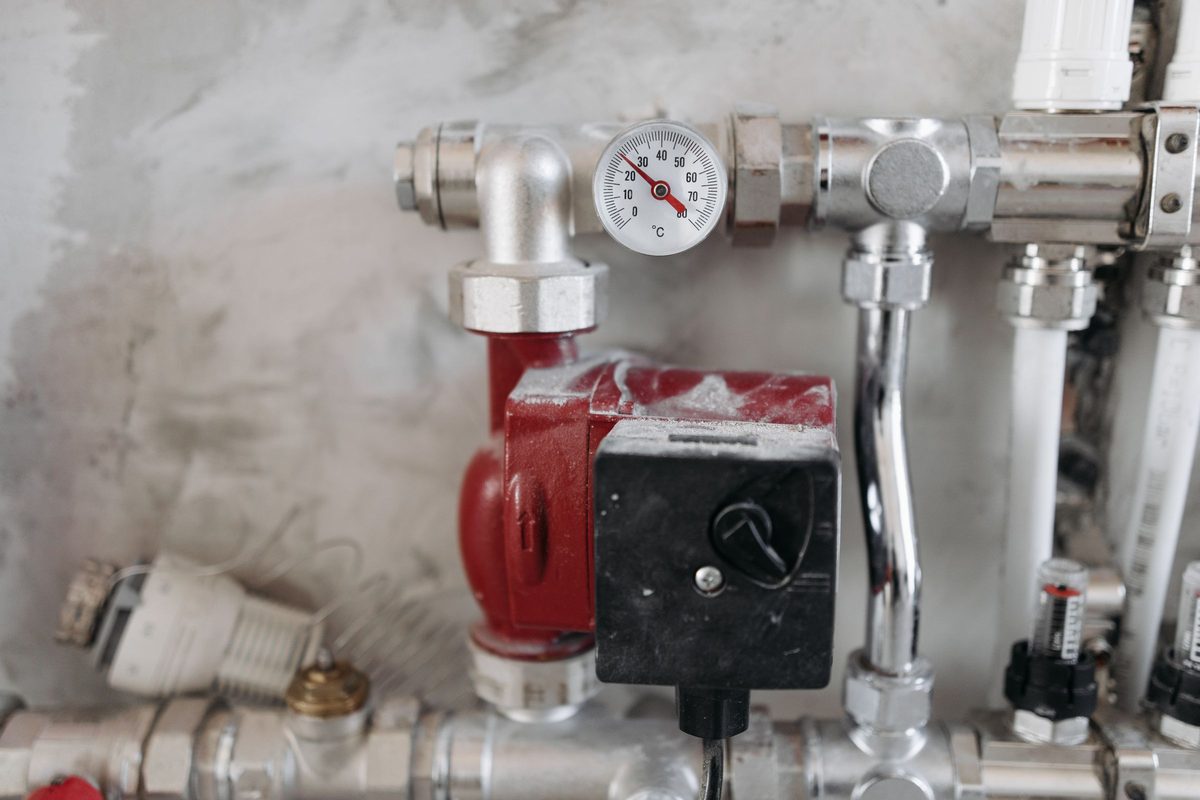 Red electric circulating pump on chrome water pipes with a temperature gauge